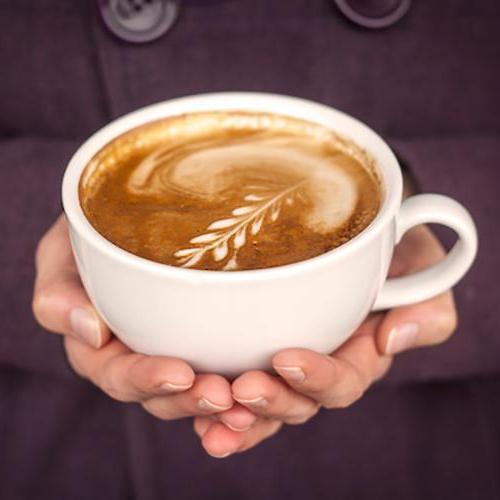 Close-up of hands holding a latte with latte art